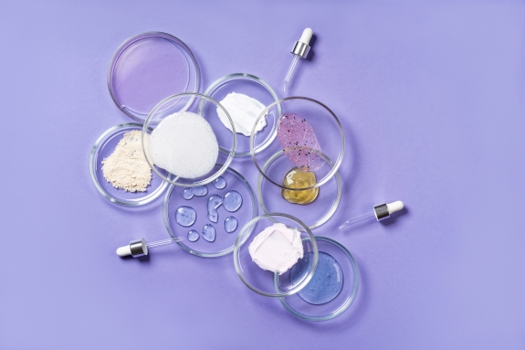 Cosmetic products, scrub, face serum, and gel in many petri dishes.