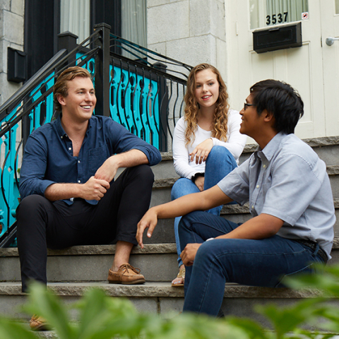 Group of smiling young students, sitting on stairs