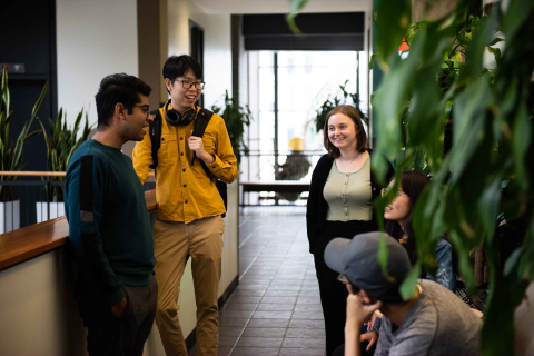 A group of 4 students hanging out in the Brown Building hallway