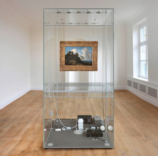 Landscape painting with golden frame enclosed in a large glass display case