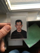 Ali Koc holding a passport photo of themselves