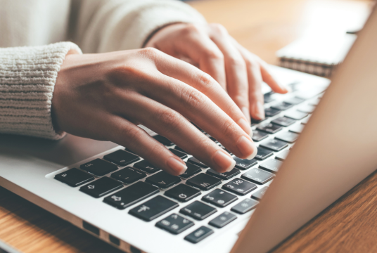 A pair of hands typing on a laptop