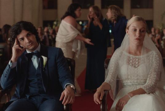 A man and a woman dancing in front of a yellow truck.