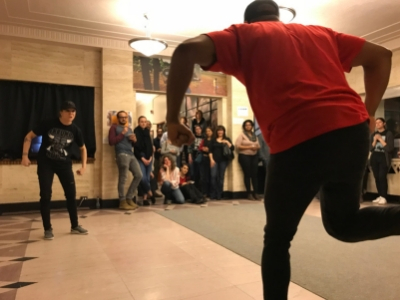 2 students playing a game in a classroom with other students looking on