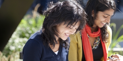 Two students looking down and smiling at something out of view