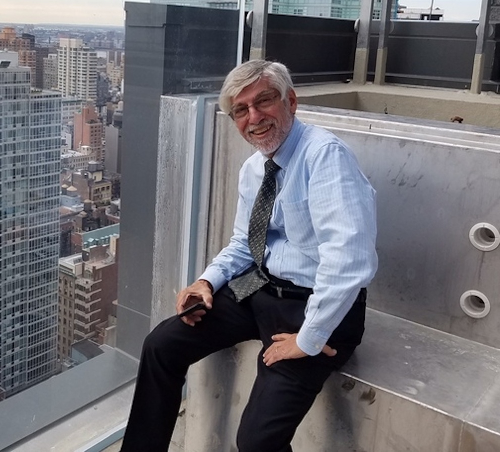 Karl Fischer sitting on a rooftop, overlooking the city.