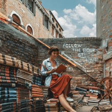 a girl reading a book while sitting on a pile of books