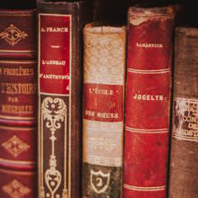 few red colored hard bound books arranged vertically 