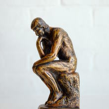 a bronze sculpture of a person thinking about an idea