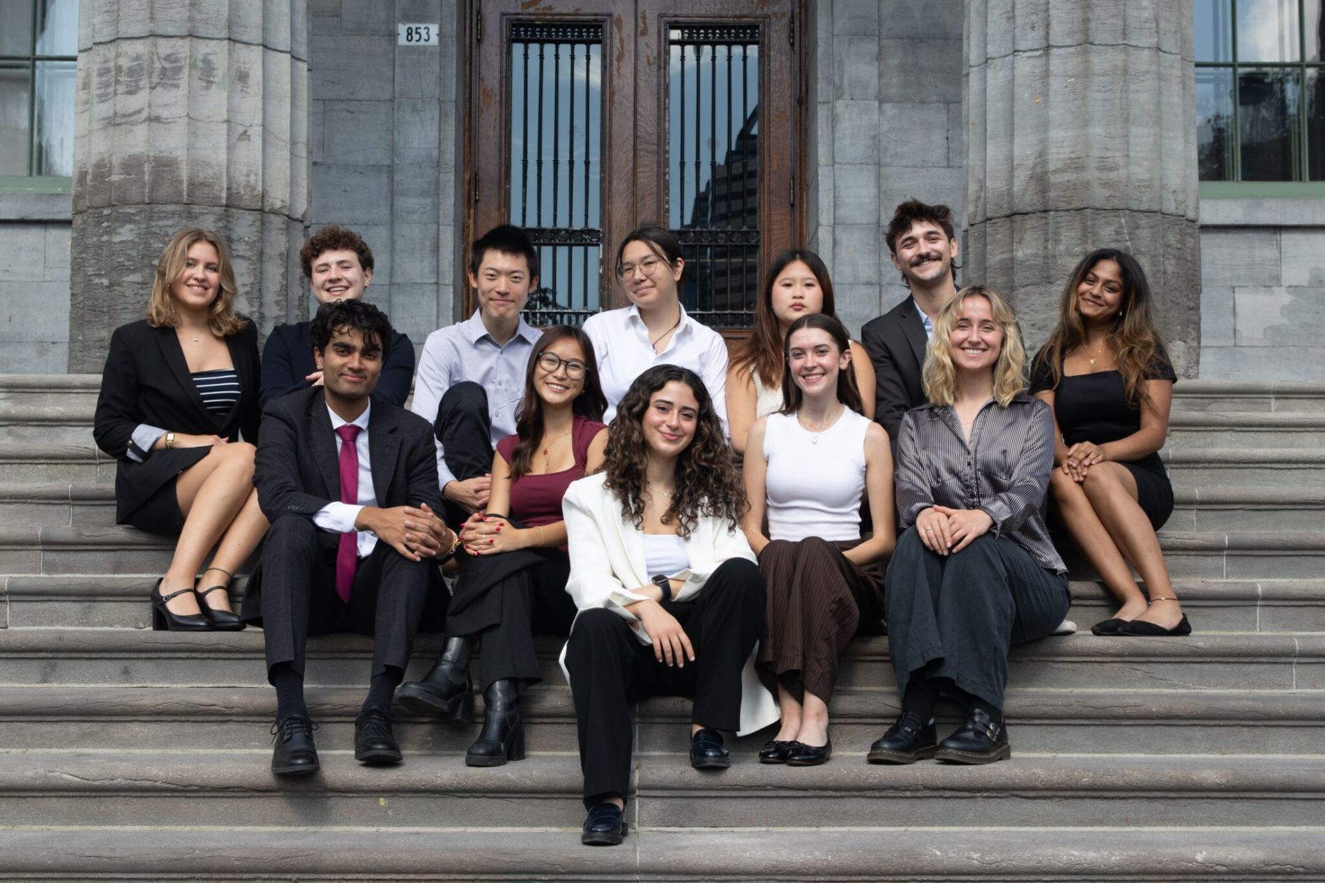 a group of students sit on the steps of a building 