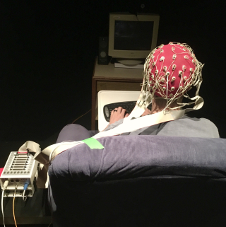 Dr. Chris Blair wearing an EEG recording device and sitting in a chair. 