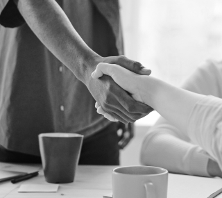 Handshake over coffee mugs