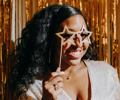 Girl holding stars to her eyes with shiny background, celebration style