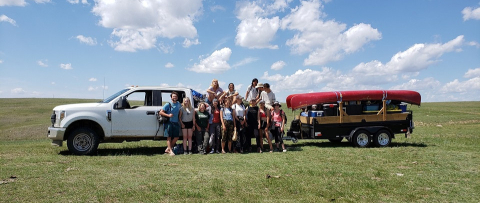 group photo of students next to a pick-up truck in the field