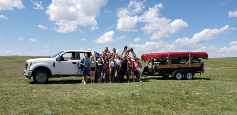 students standing in front of truck in a field
