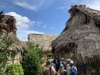 A photograph of students in Panama, surrounded by houses with thatched roofs participating in the Panama Field Study Semester.