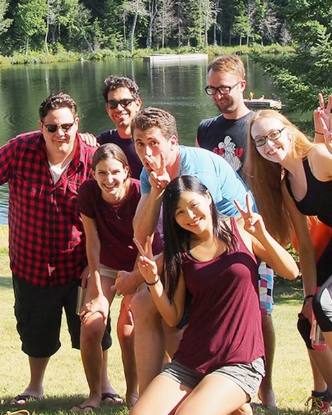 Students posing in front of a lake in the summertime