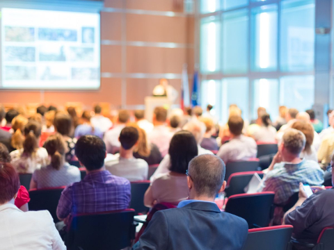 auditorium full of people looking at a presentation with a screen