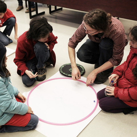 Young students sitting in a circle, working on a project