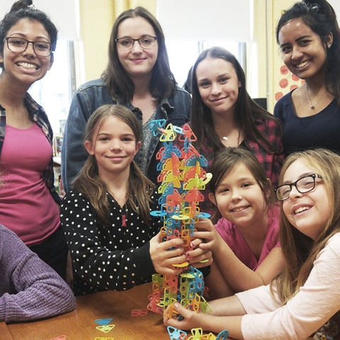 students holding a structure in a classroom