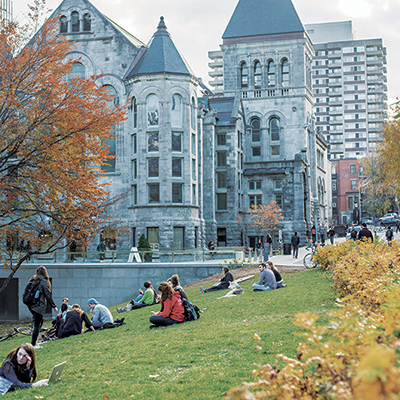 students sitting on the lawn on campus in the fall