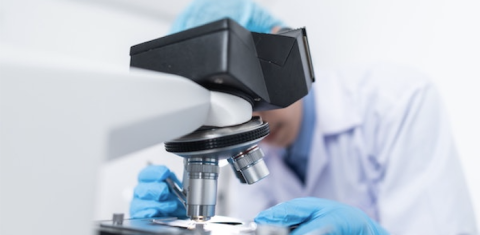person looking into microscope in lab