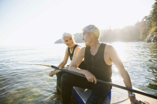 An older man and woman on a paddle board in a river