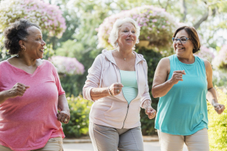 three older women jogging together and smiling