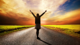 happy woman standing on a long road with her hands up