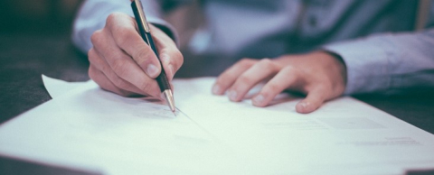 Person signing a document with a black pen