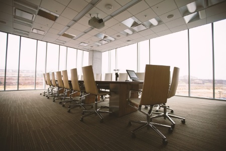 A dark office with one long table and floor-to-ceiling windows