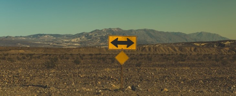 Yellow road sign with an arrow pointing left and right