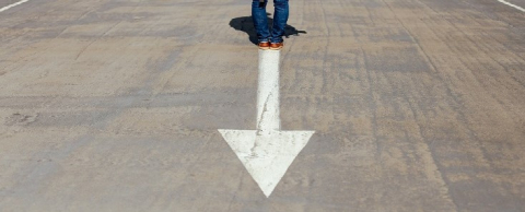 Overhead view of a painted white arrow on concrete