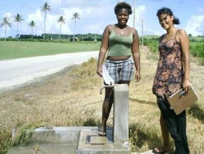 Assistant Kim McGrath posing with a woman washing clothes 