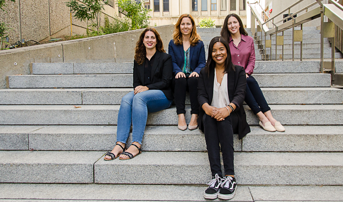 The four members of the CDO team sitting sitting on the steps to New Chancellor Day Hall. 