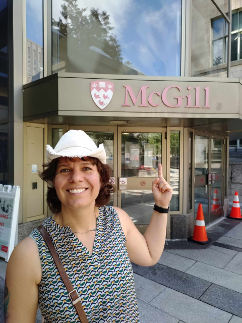 photo d'Hélène Laurin montrant du doigt l'enseigne de McGill en souriant