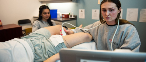 Person lying down with two girls performing test