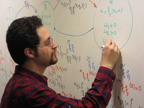 man writing equations on whiteboard