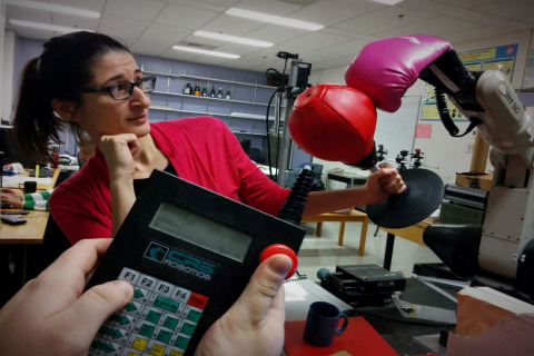 woman interacting with a robotic boxing glove with it's controls held in the foreground