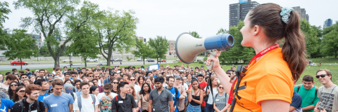 A student volunteer uses a megaphone to address a crowd during orientation.