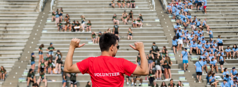 volunteer in reg t-shirt standing before crowd