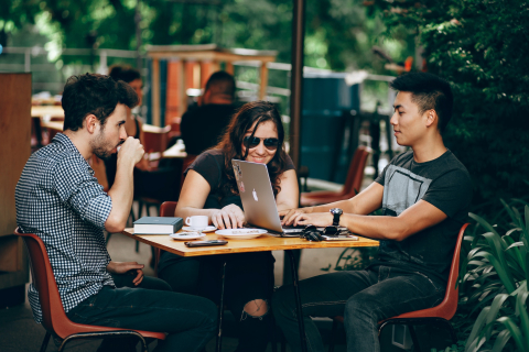 A group of students working together at a cafe table outdoors 