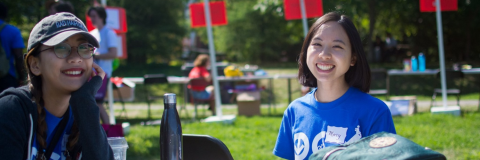 Two smiling students sit together on lower campus