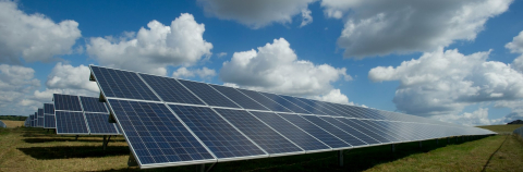 Solar panels on the ground with blue sky and white clouds in background