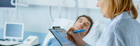 Female physician at bed side of male patient records data