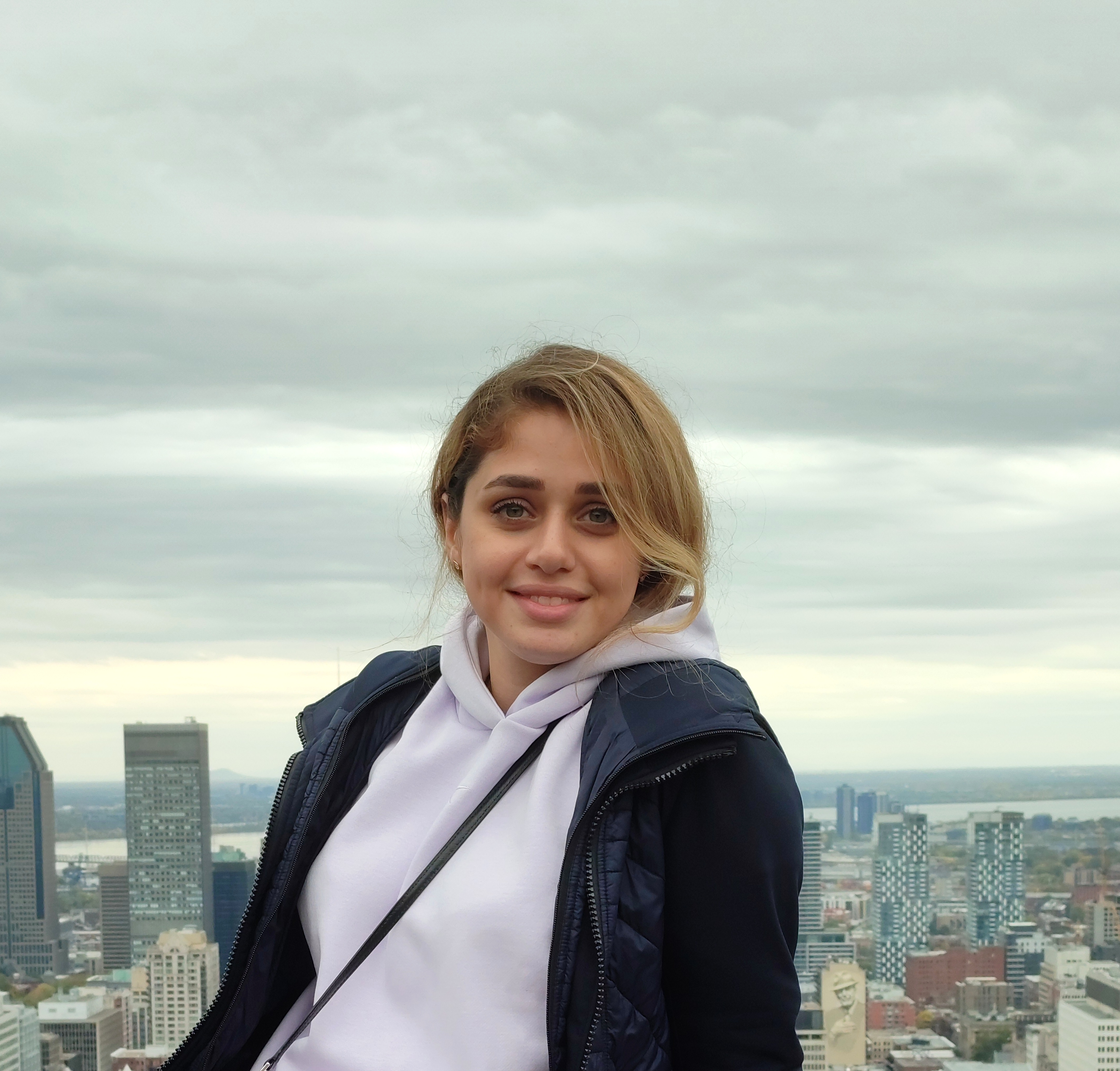 Portrait of Farimah Tikhani - young woman in front of a Montreal view smiling at the camera 