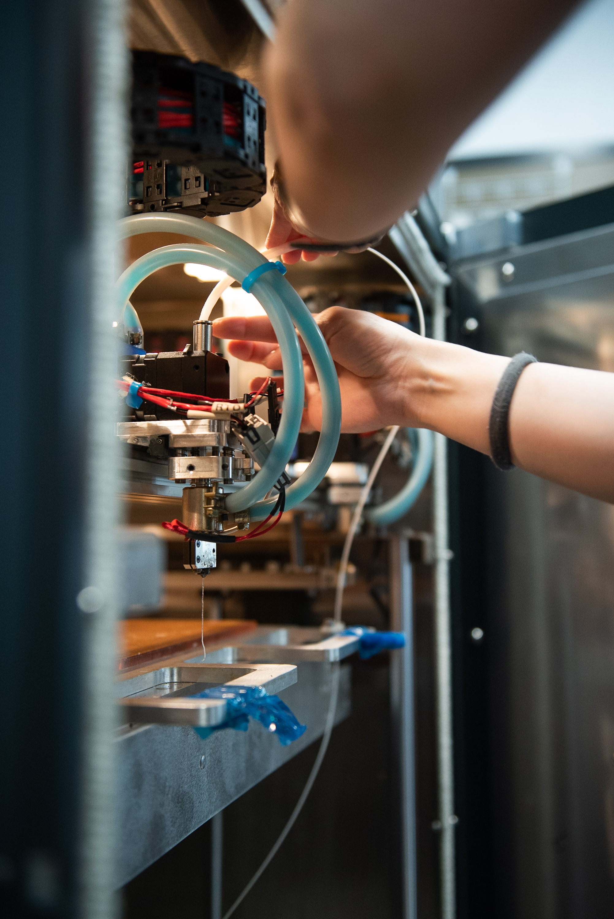 Hands loading a filament in a 3D printer hot head