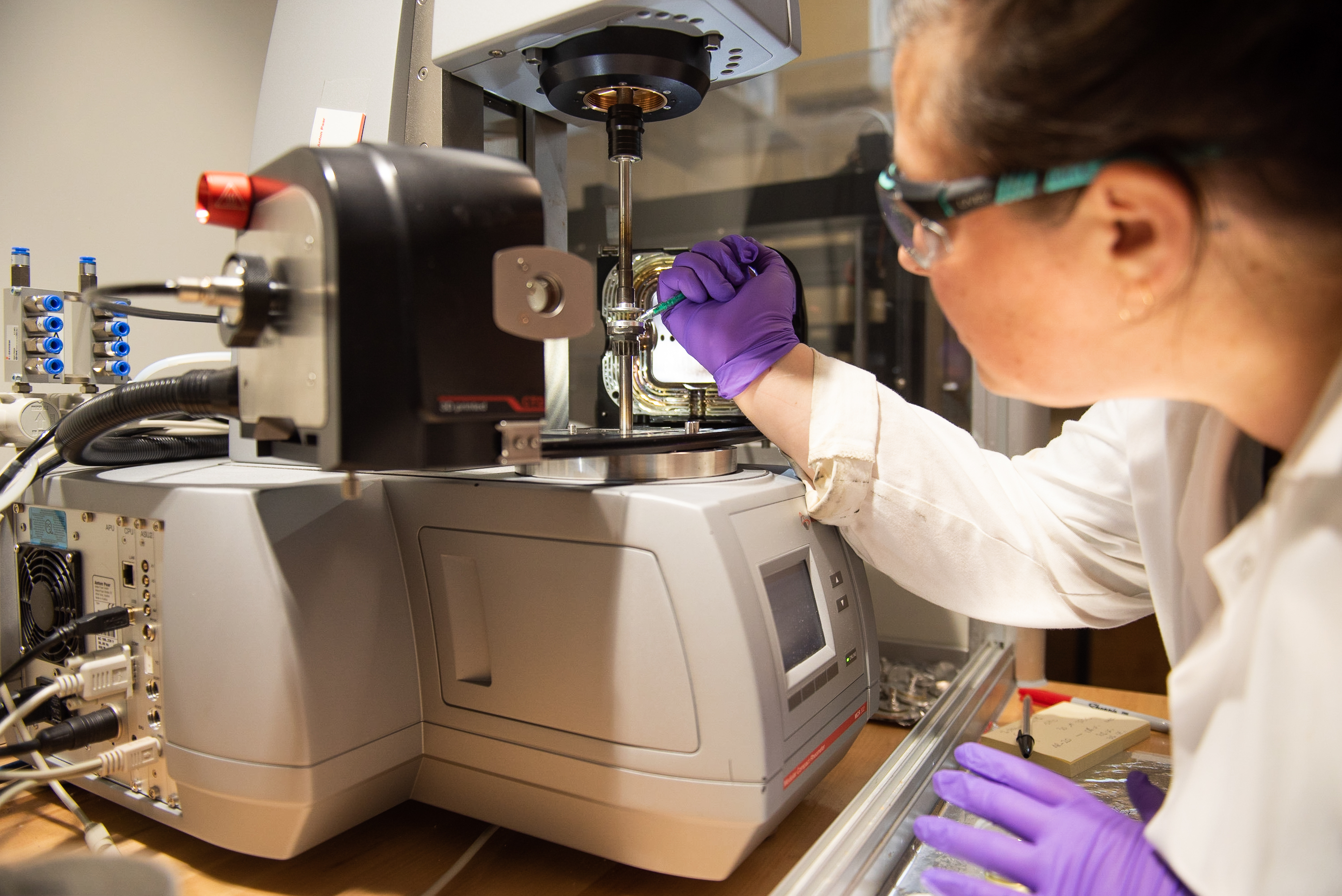 Young woman is loading the rheometer with a sample using a syringe