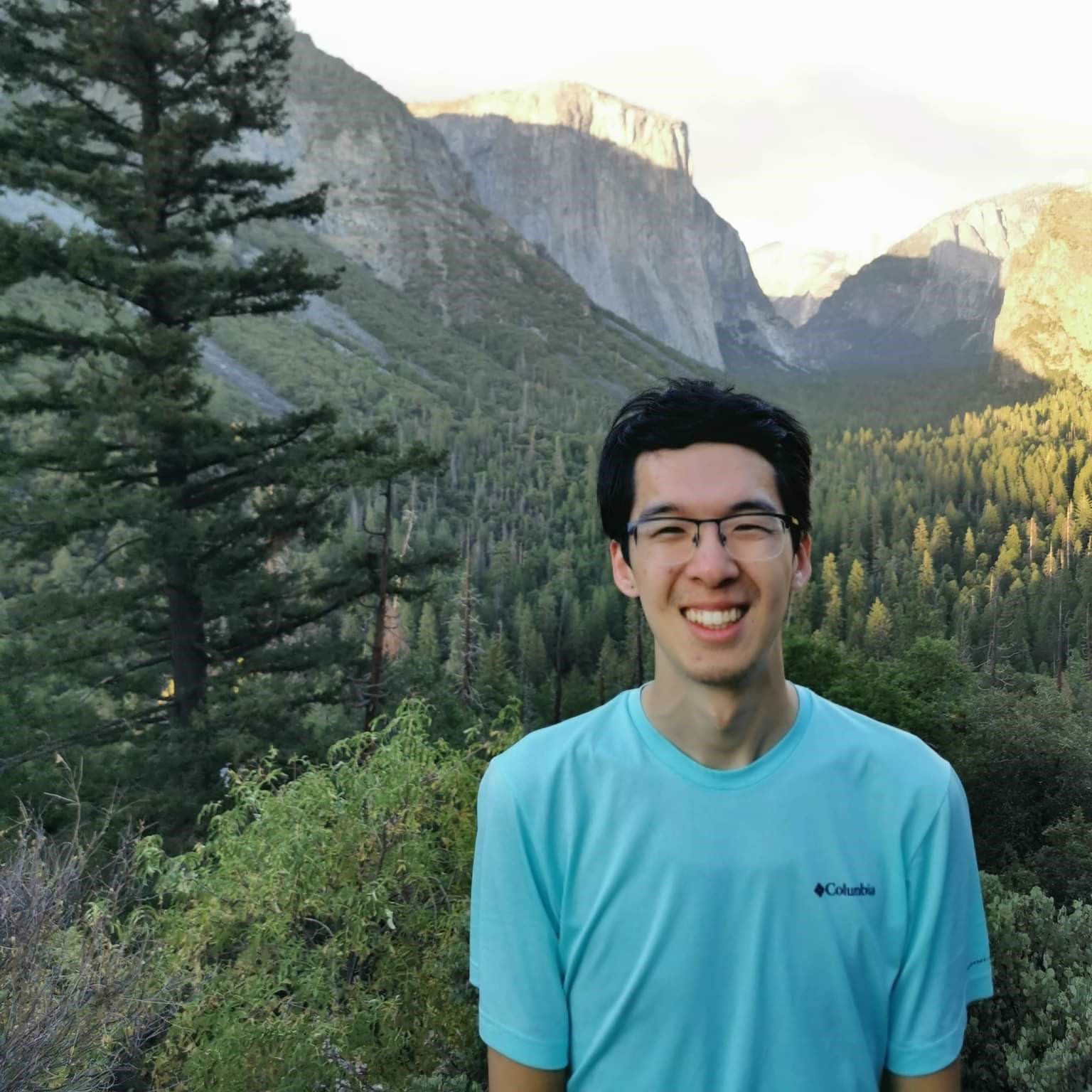Portrait of Jimmy smiling in front of a wilderness and mountain landscape