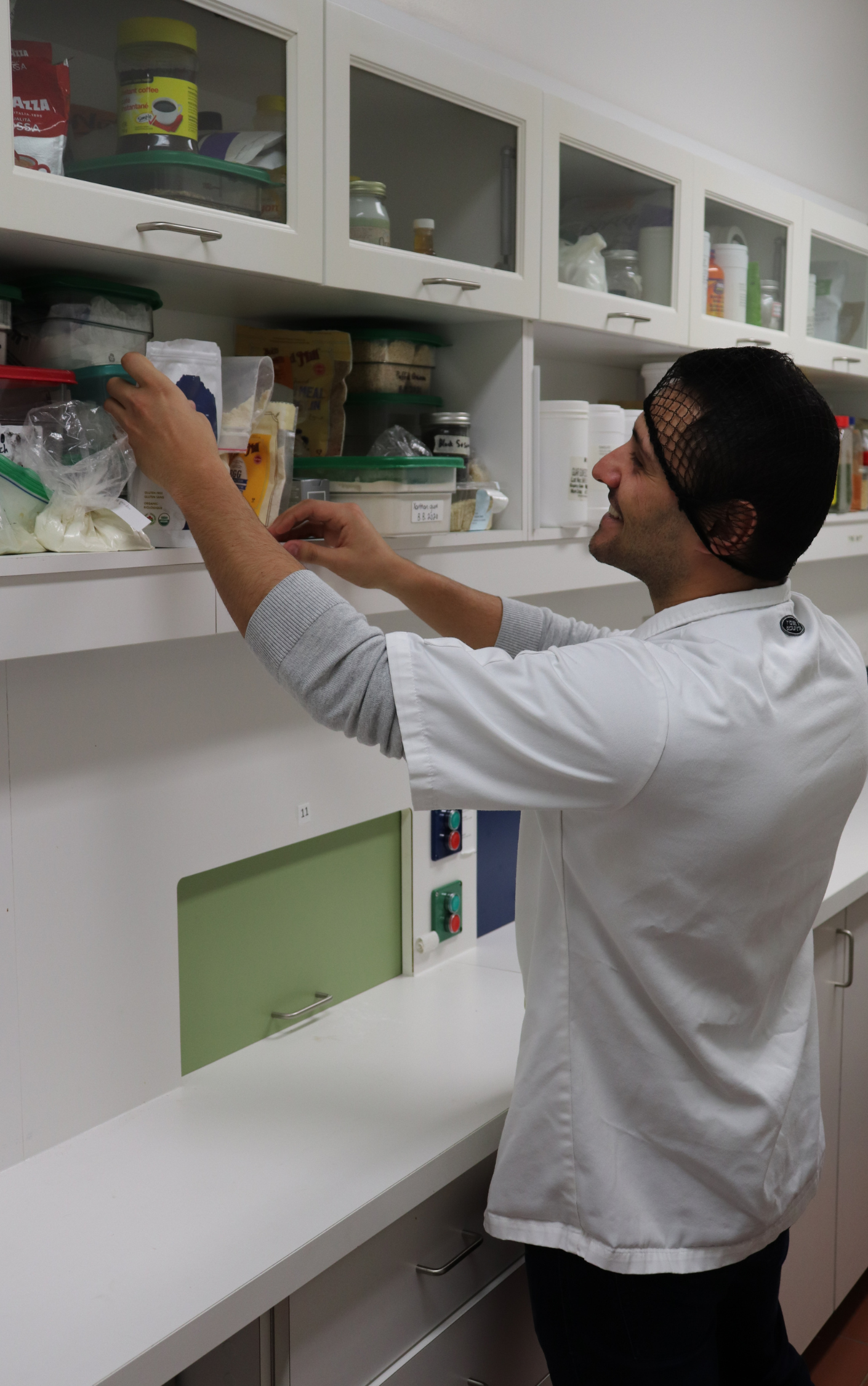 Student retrieving ingredients from a cupboard.